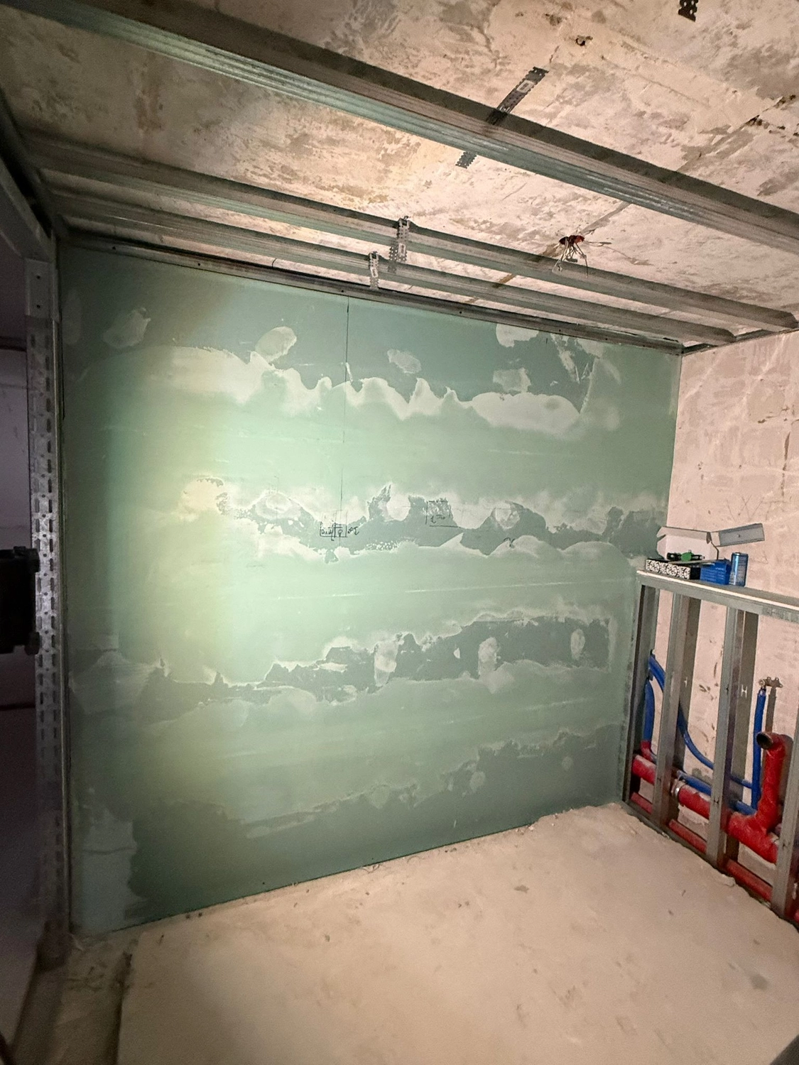 Spanndecken Grunau - Sanierung, Renovierung & Innenausbau - Nahaufnahme einer grünen Gipskartonwand mit weißer Fugenmasse an den horizontalen Fugen.