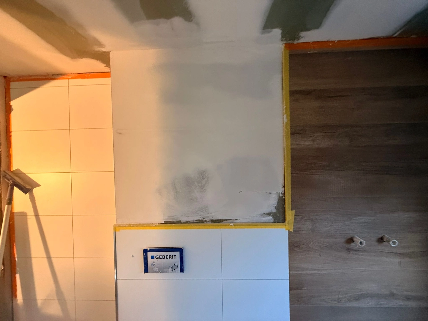 Spanndecken Grunau - Sanierung, Renovierung & Innenausbau - Verputzte Gipskartonwand über neu verlegten weißen Wandfliesen mit blauem Geberit-Schutzetikett.