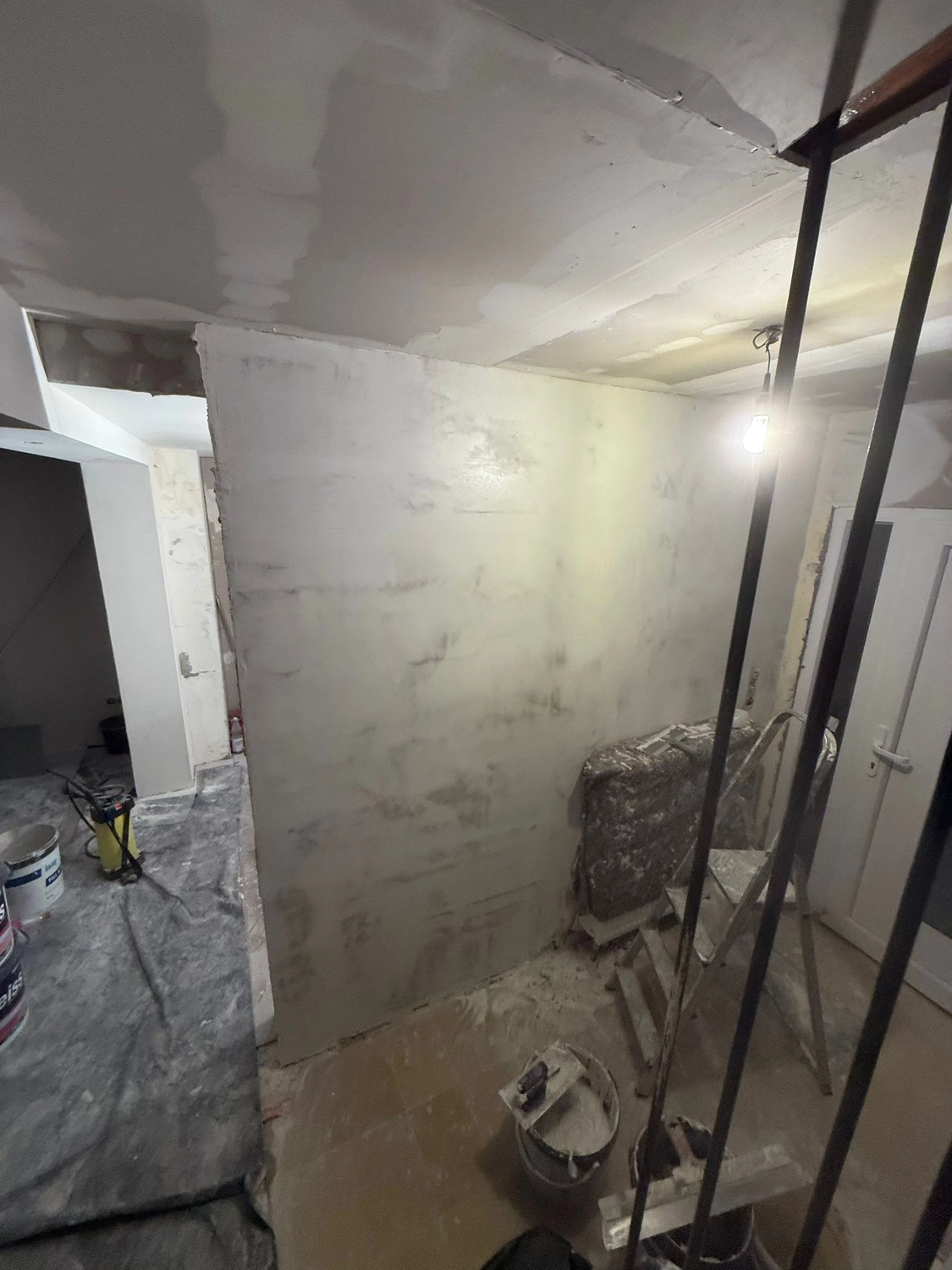Spanndecken Grunau - Sanierung, Renovierung & Innenausbau - Schwach beleuchteter Innenraum während der Renovierung mit verspachtelten Gipskartonfugen und Stützpfeilern.
