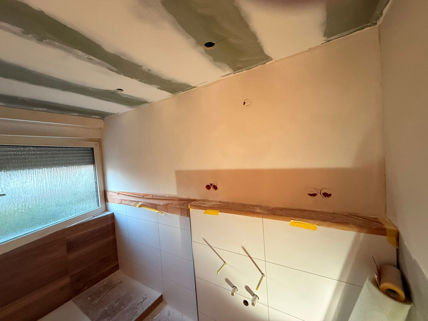 Spanndecken Grunau - Sanierung, Renovierung & Innenausbau - Badezimmer-Renovierungsbereich mit gefliesten unteren Wänden, verklebten Kanten und ungestrichenen Gipskartonplatten.
