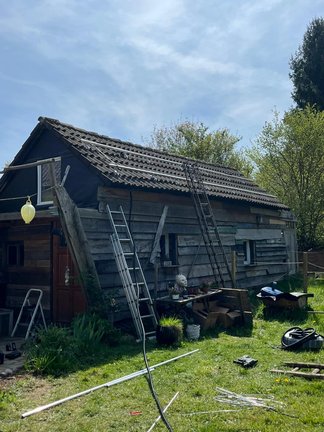 Spanndecken Grunau - Sanierung, Renovierung & Innenausbau - Eine große Anlage aus modernen schwarzen Solarmodulen, installiert auf einem steilen, dunkel gedeckten Ziegeldach unter strahlend blauem Himmel.