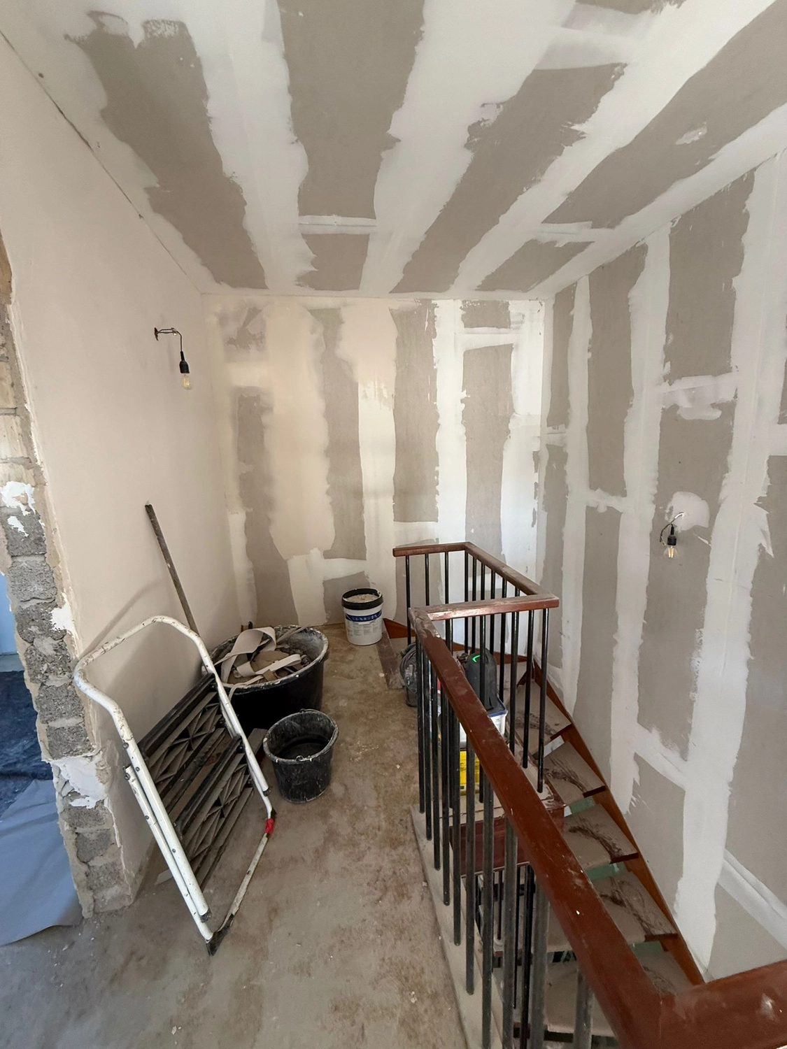 Spanndecken Grunau - Sanierung, Renovierung & Innenausbau - Gipskartonarbeiten in der Nähe eines hölzernen Treppengeländers.