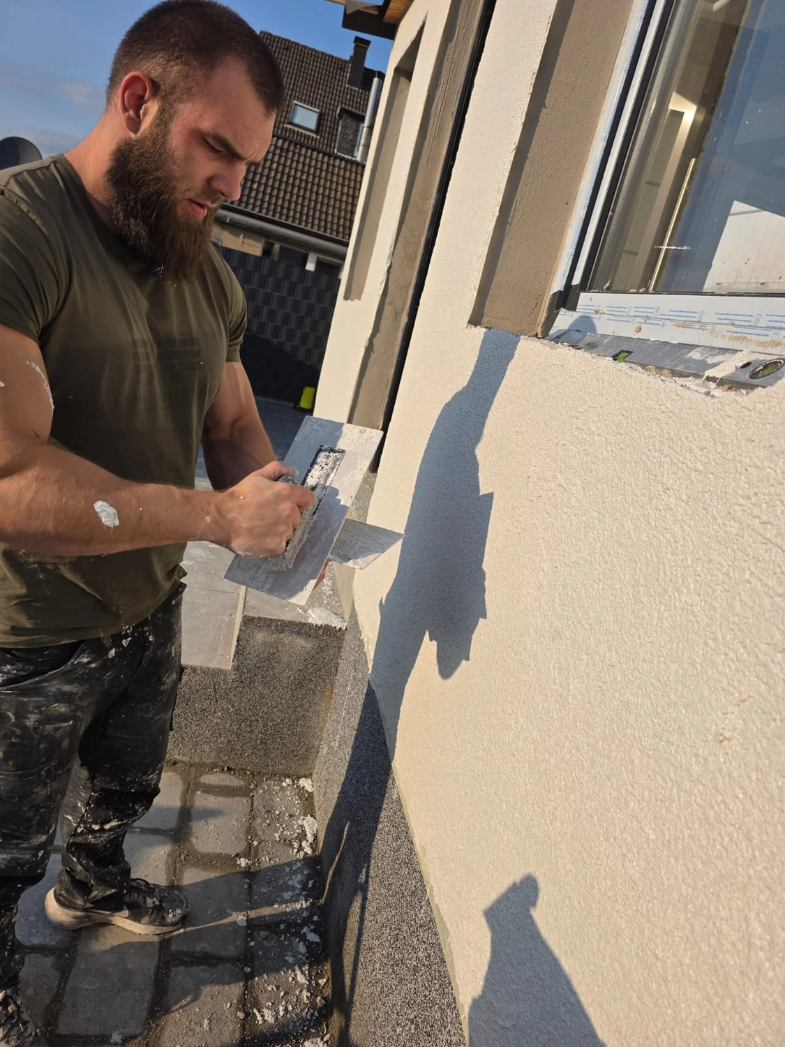 Spanndecken Grunau - Sanierung, Renovierung & Innenausbau - Nahaufnahme eines Arbeiters, der die Struktur einer neuen Außenwandbeschichtung verfeinert.