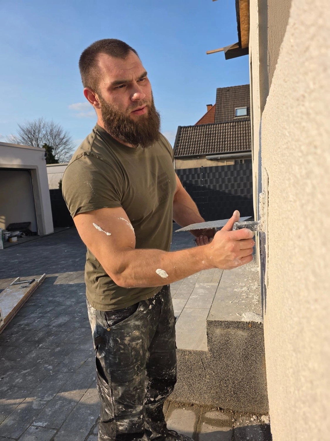 Spanndecken Grunau - Sanierung, Renovierung & Innenausbau - Ein Mann trägt mit einer Kelle Stuck oder Putz an einer Gebäudeecke auf.