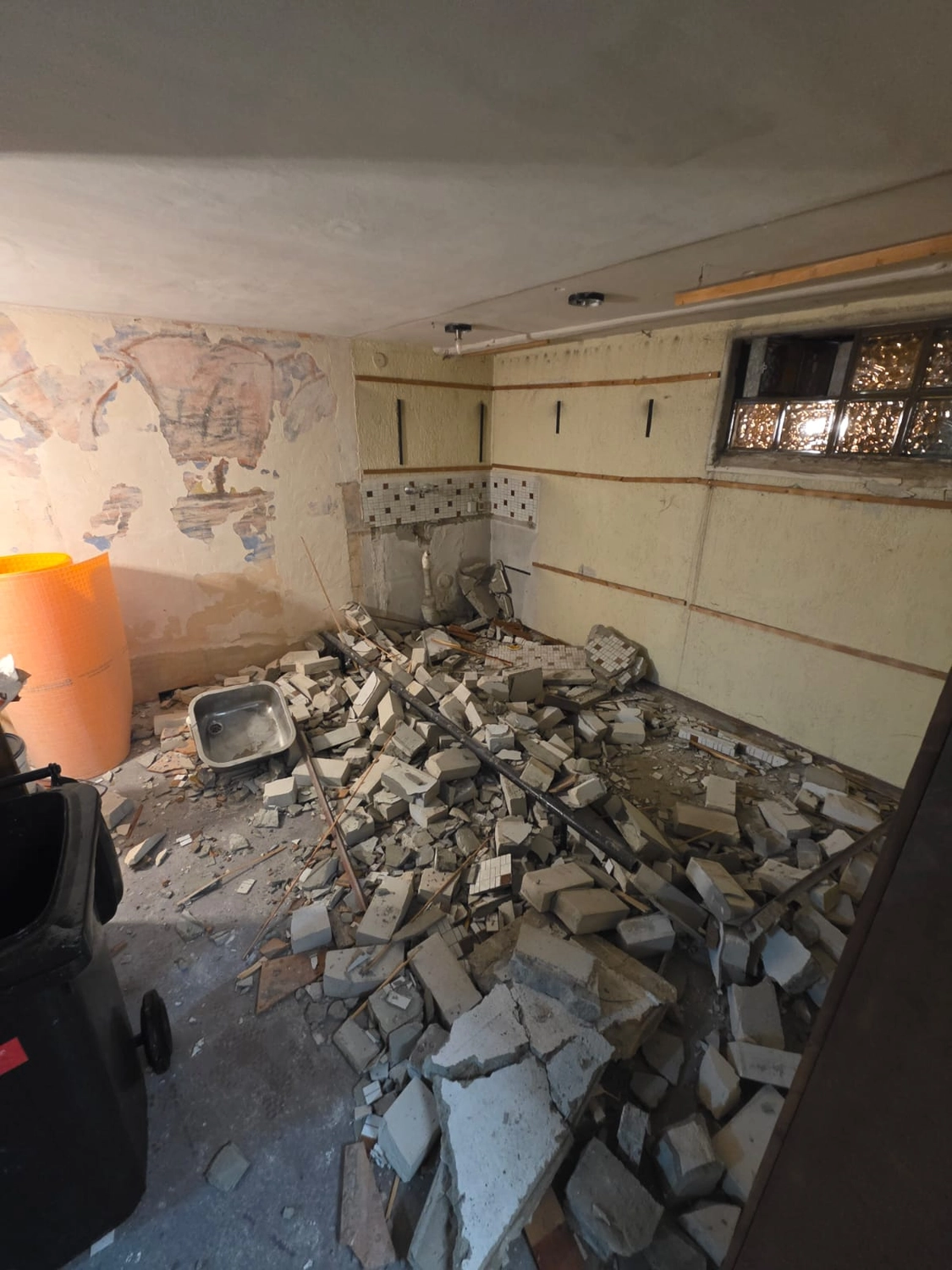 Spanndecken Grunau - Sanierung, Renovierung & Innenausbau - Ein schwach beleuchteter, unordentlicher Raum während eines Abrisses. Der Boden ist mit einem großen Haufen zerbrochener Betonblöcke, Ziegel und Gipsresten bedeckt.