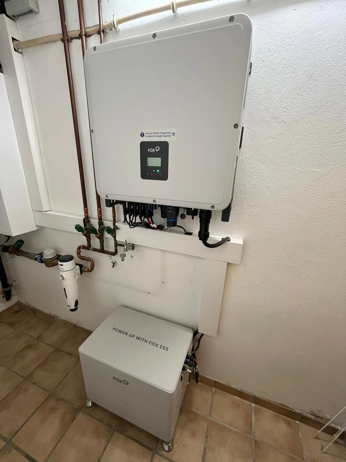 Spanndecken Grunau - Sanierung, Renovierung & Innenausbau - Ein wandmontierter Fox ESS Solarwechselrichter an einer Betonwand neben Stromverteilerkästen.