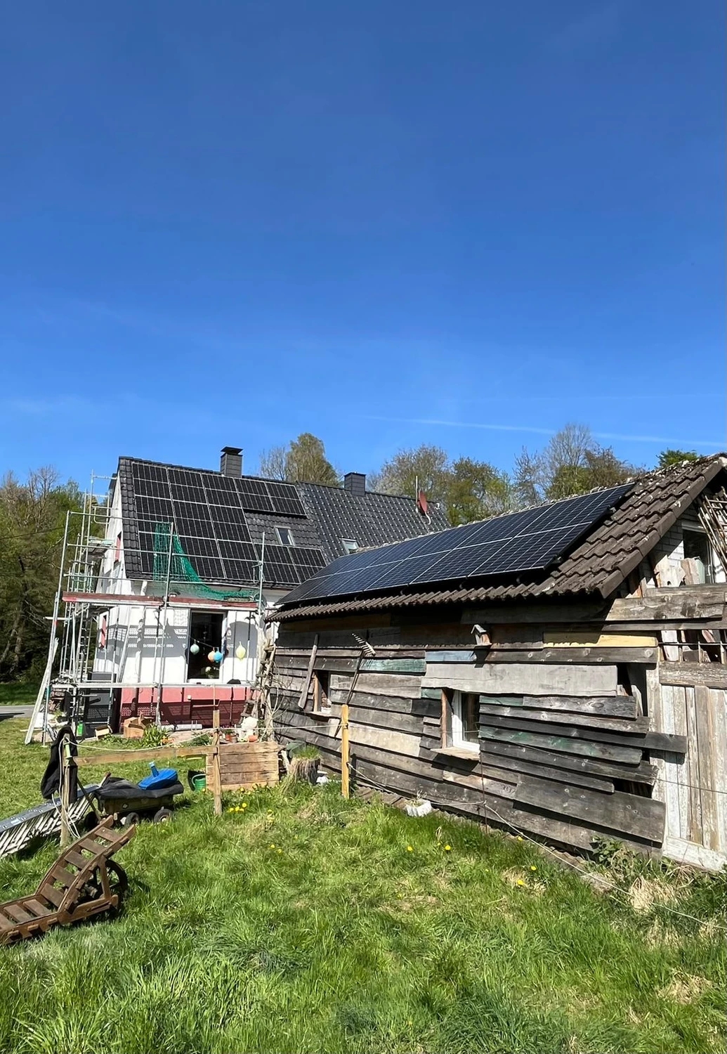 Spanndecken Grunau - Sanierung, Renovierung & Innenausbau - Eine große Anlage aus modernen schwarzen Solarmodulen, installiert auf einem steilen, dunkel gedeckten Ziegeldach unter strahlend blauem Himmel.