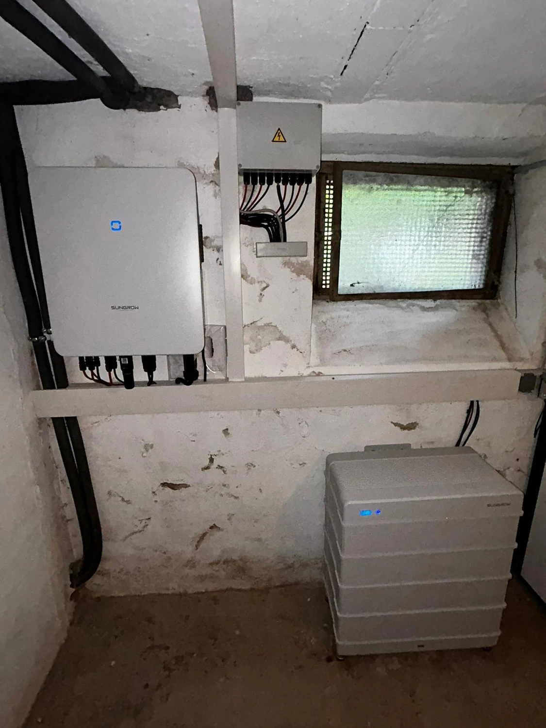 Spanndecken Grunau - Sanierung, Renovierung & Innenausbau - Ein wandmontierter Fox ESS Solarwechselrichter an einer Betonwand neben Stromverteilerkästen.