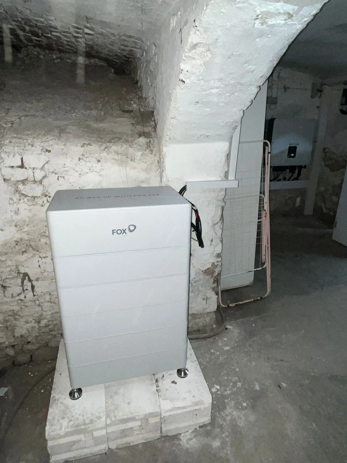 Spanndecken Grunau - Sanierung, Renovierung & Innenausbau - Ein wandmontierter Fox ESS Solarwechselrichter an einer Betonwand neben Stromverteilerkästen.